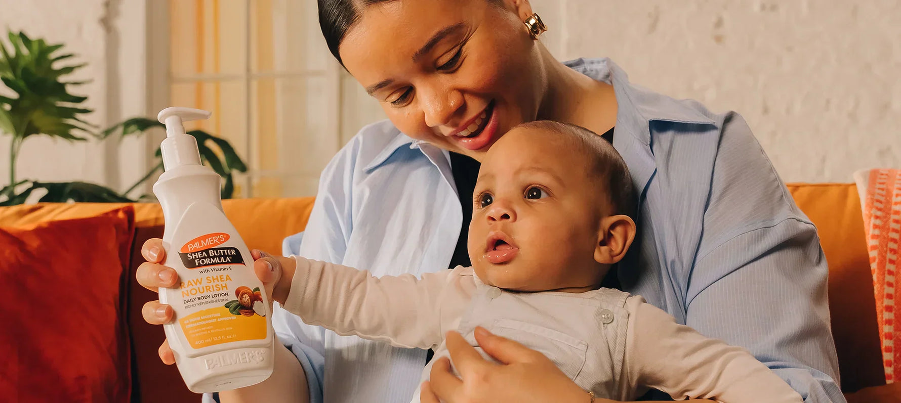 Woman holding baby and bottle of Palmer's Shea Butter Formula Body Lotion