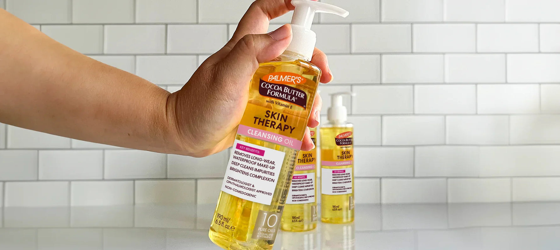 Hand holding bottle of Palmer's Skin Therapy Cleansing Oil in bathroom
